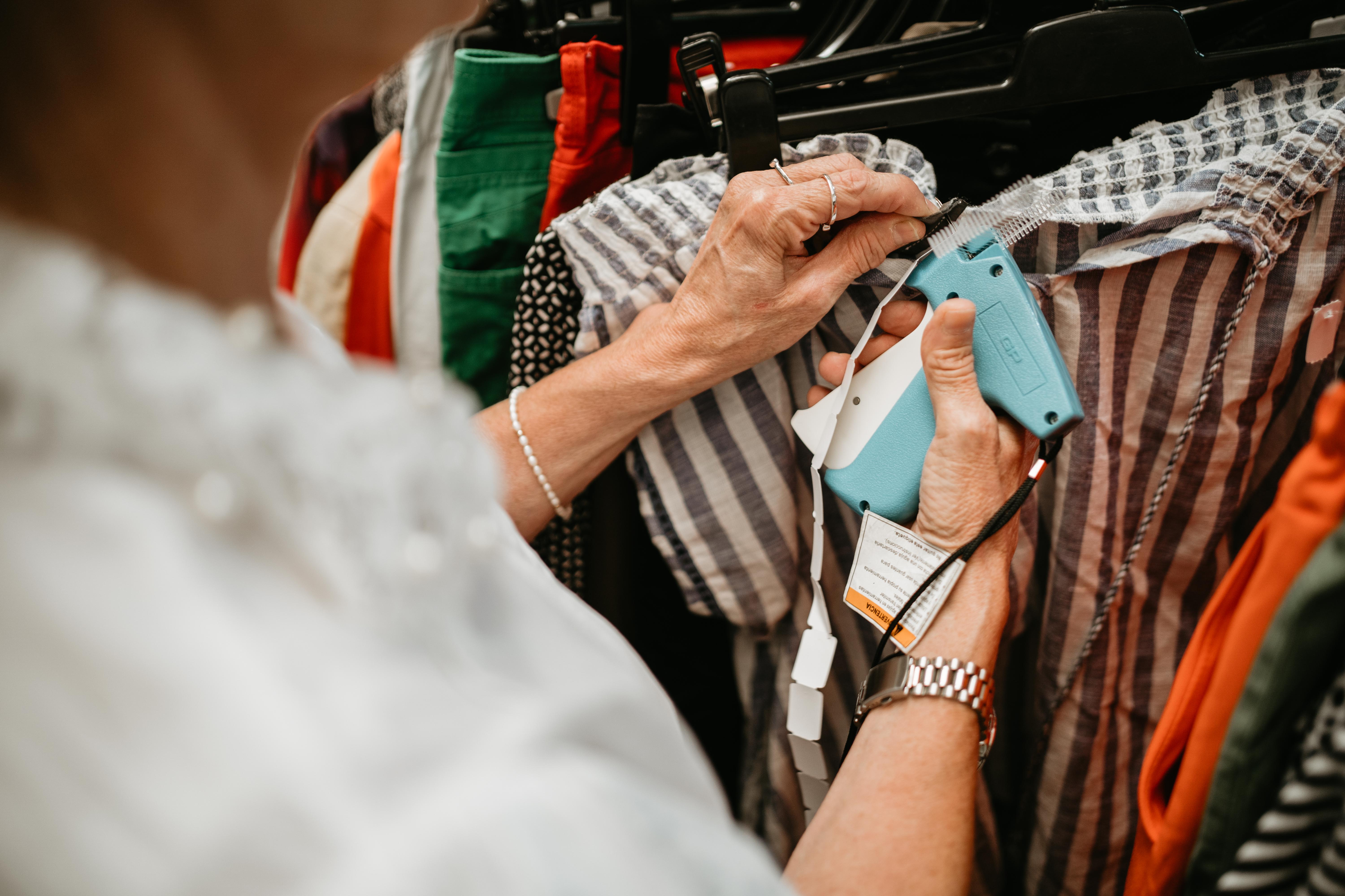 Une dame accroche des étiquettes sur des vêtements