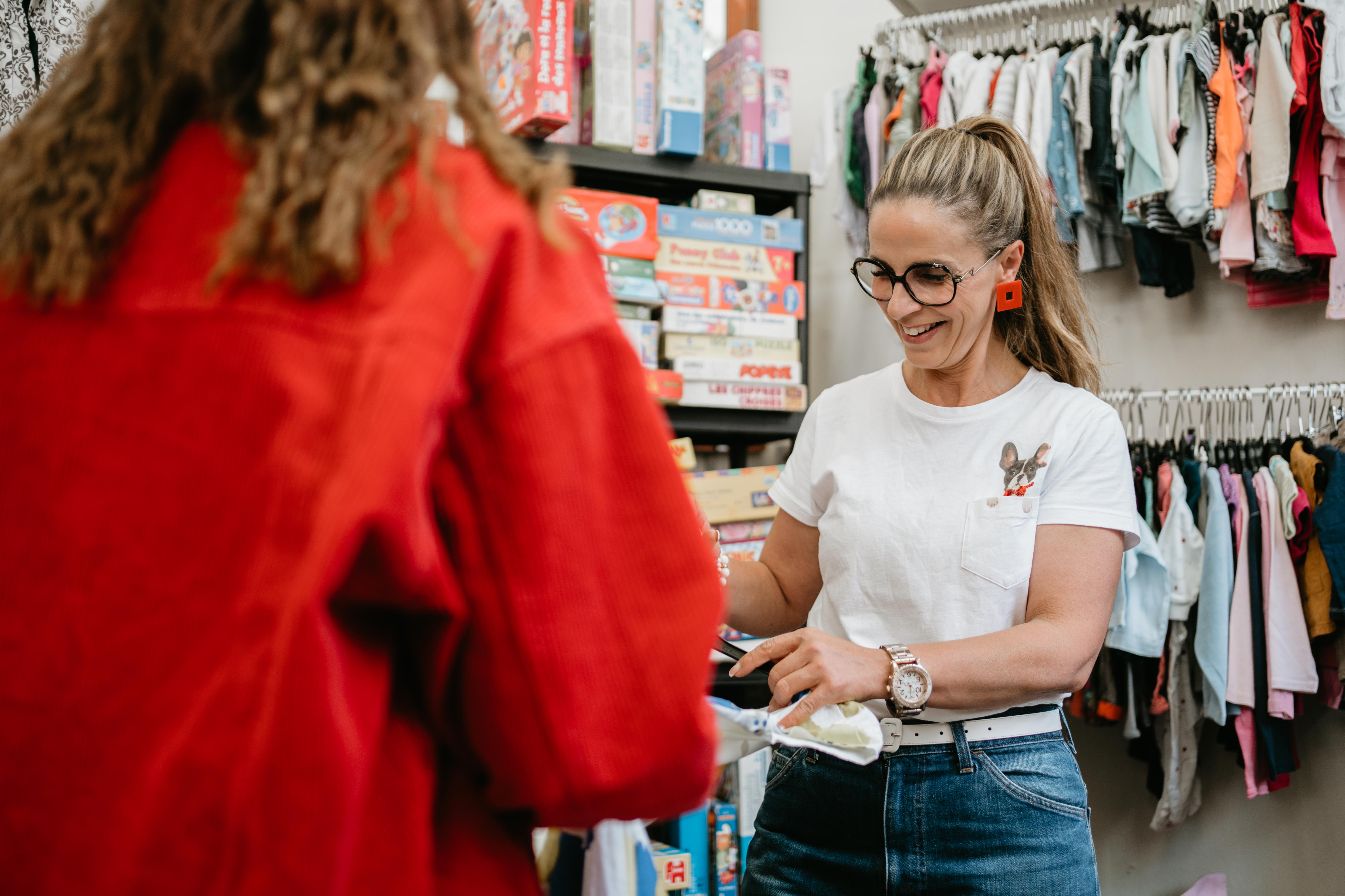 Une dame avec un t-shirt blanc souriante dans un magasin avec des jeux et des vêtements